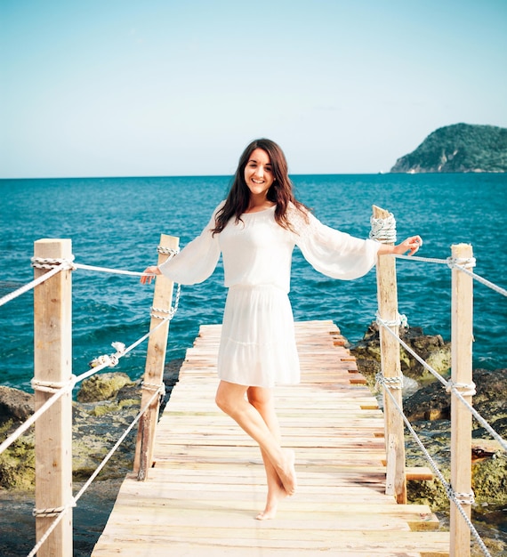 Jovem mulher feliz na ponte perto do horário de verão do mar