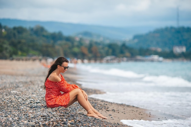 Jovem mulher feliz na praia com vista para a montanha