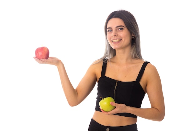 Jovem mulher feliz no top preto segurando duas maçãs no fundo branco no estúdio