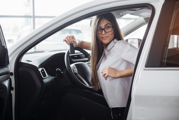 Jovem mulher feliz perto do carro com as chaves na mão