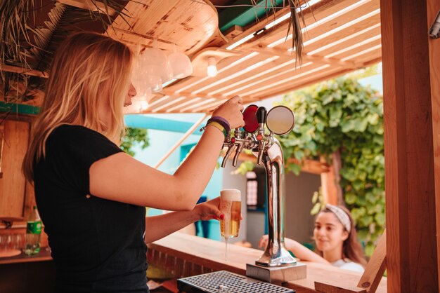 Jovem mulher feliz servindo cerveja para uma mulher caucasiana