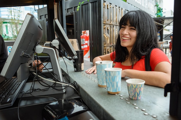 Jovem mulher feliz sorrindo pedindo sua comida no caminhão de fast food