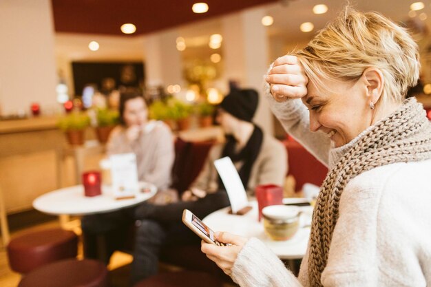 Jovem mulher feliz usando smartphone em um café