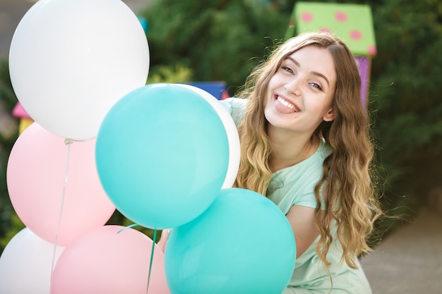 Jovem mulher feliz voando em balões multicoloridos em um dia ensolarado