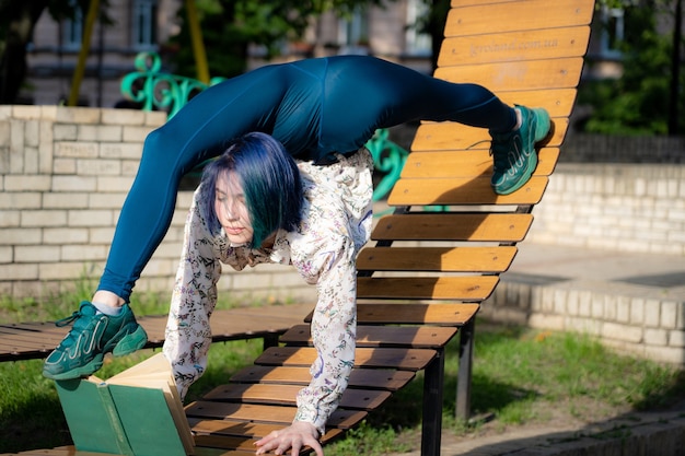 Foto jovem mulher flexível lendo livro no banco, dobrando as costas. conceito de individualidade, criatividade e educação. foto de alta qualidade