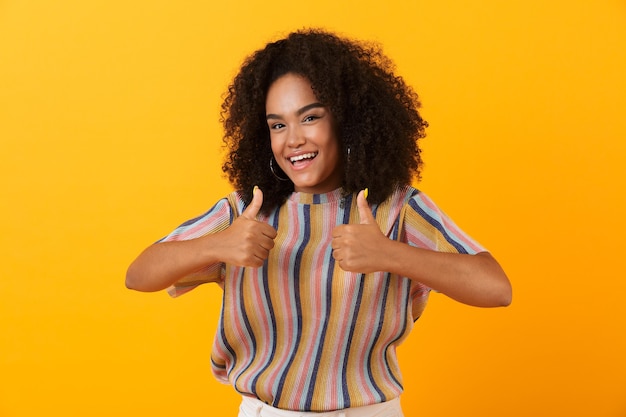 Foto jovem mulher fofa posando isolada na parede amarela fazendo gesto de polegar para cima