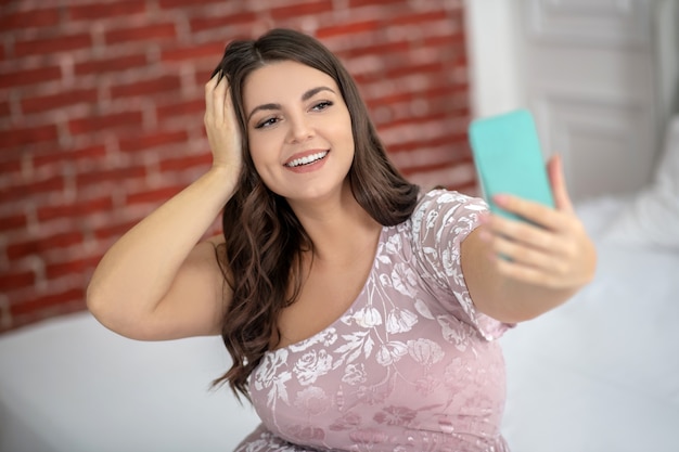 Jovem mulher gordinha fazendo selfie e parecendo feliz
