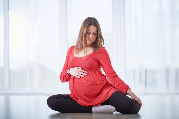 Jovem mulher grávida bonita fazendo yoga asana Vamadevasana