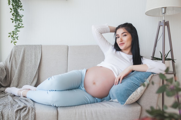 Jovem mulher grávida dentro de casa. Closeup retrato de mulher esperando. Linda fêmea esperando seu nascimento do bebê.