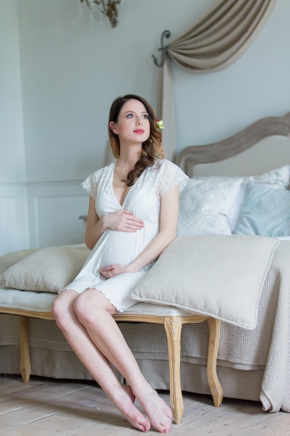 Jovem, mulher grávida, em, vestido branco, sentando