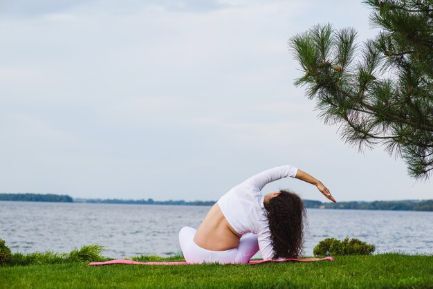 Jovem mulher grávida fazendo yoga ao ar livre