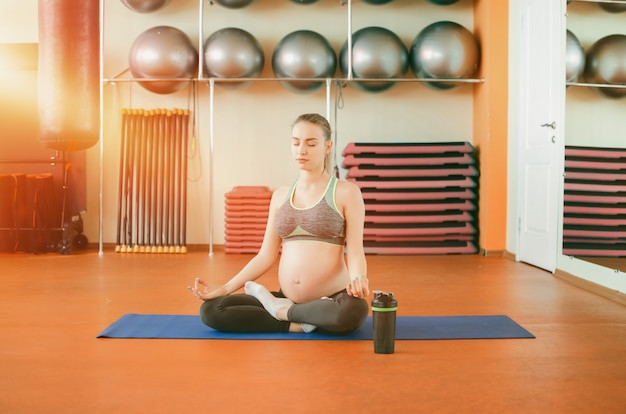 Jovem mulher grávida fazendo yoga