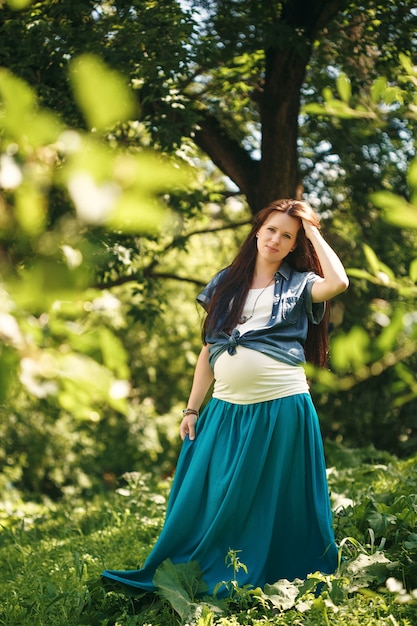 Jovem mulher grávida no parque de verão