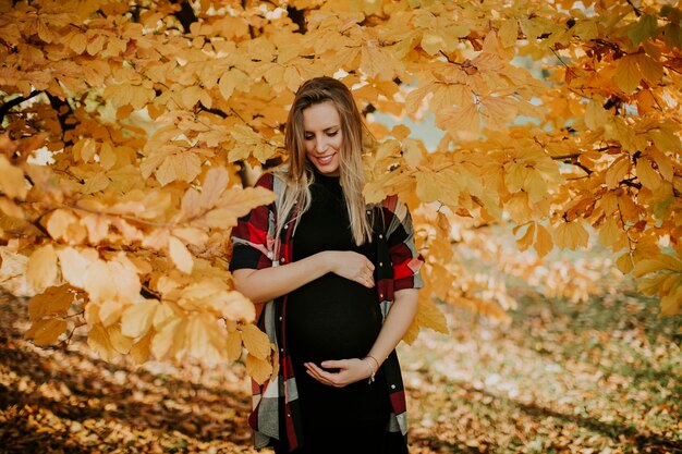 Jovem mulher grávida no parque outono