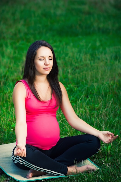 Jovem mulher grávida relaxando no parque ao ar livre, gravidez saudável.