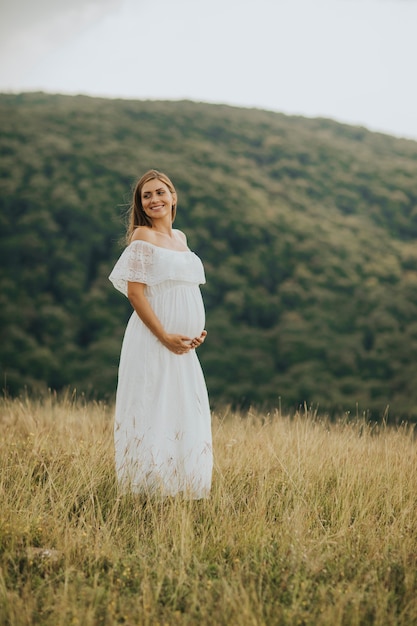 Jovem mulher grávida relaxante fora na natureza