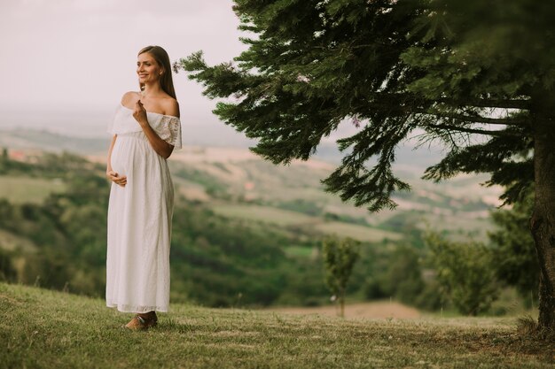 Jovem mulher grávida relaxante fora na natureza