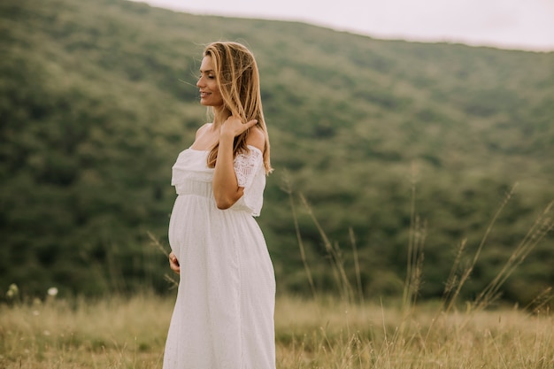 Jovem mulher grávida relaxante fora na natureza