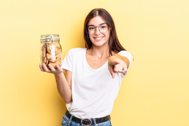 Jovem mulher hispânica, apontando para a câmera escolhendo você. conceito de garrafa de biscoitos