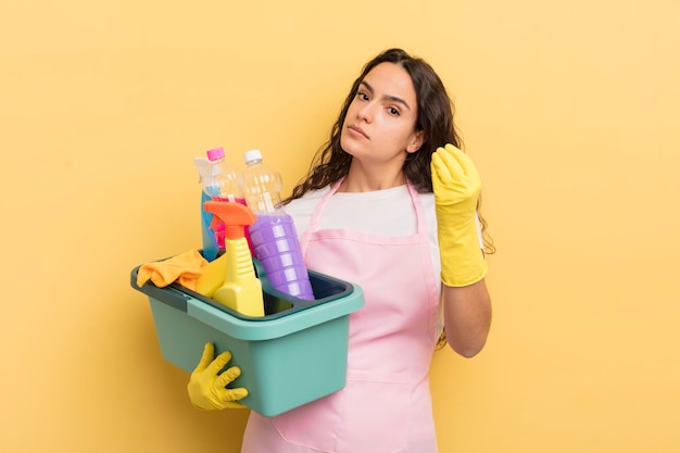 Jovem mulher hispânica bonita fazendo gesto de capice ou dinheiro dizendo para você pagar o trabalho doméstico um conceito de produtos limpos