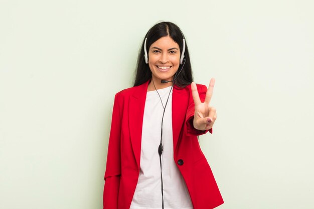 Jovem mulher hispânica bonita sorrindo e parecendo amigável mostrando o conceito de telemarteker número dois