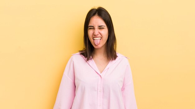 Foto jovem mulher hispânica com alegre atitude rebelde despreocupada brincando e enfiando a língua para fora se divertindo