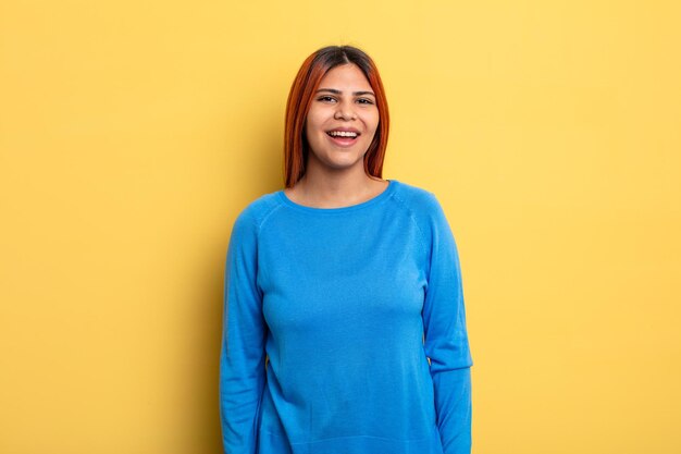 Jovem mulher hispânica com um sorriso grande, amigável e despreocupado, parecendo positivo, relaxado e feliz, arrepiante