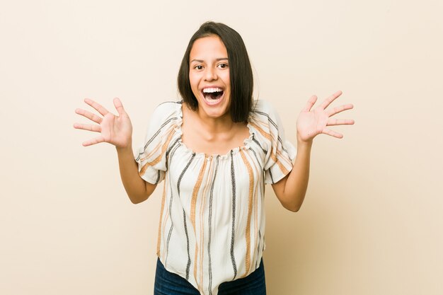 Jovem mulher hispânica comemorando uma vitória ou sucesso, ele fica surpreso e chocado