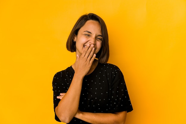 Jovem mulher hispânica em amarelo rindo de emoção feliz, despreocupada e natural.