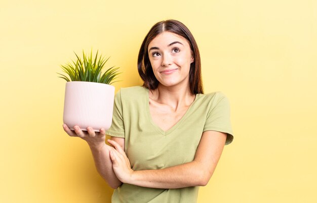 Jovem mulher hispânica encolhendo os ombros, sentindo-se confusa e incerta. conceito de vaso de planta