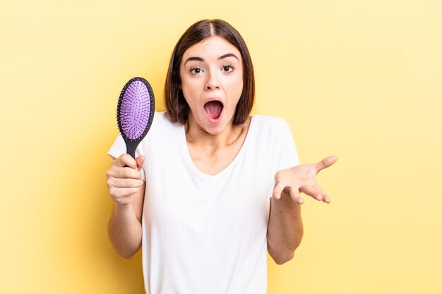 Jovem mulher hispânica espantada, chocada e atônita com uma surpresa inacreditável. conceito de escova de cabelo