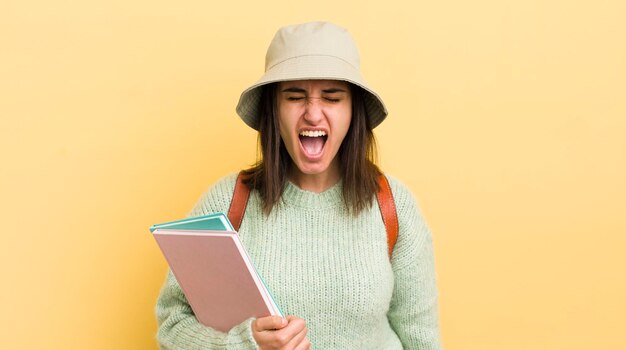 Jovem mulher hispânica gritando agressivamente olhando o conceito de estudante muito irritado