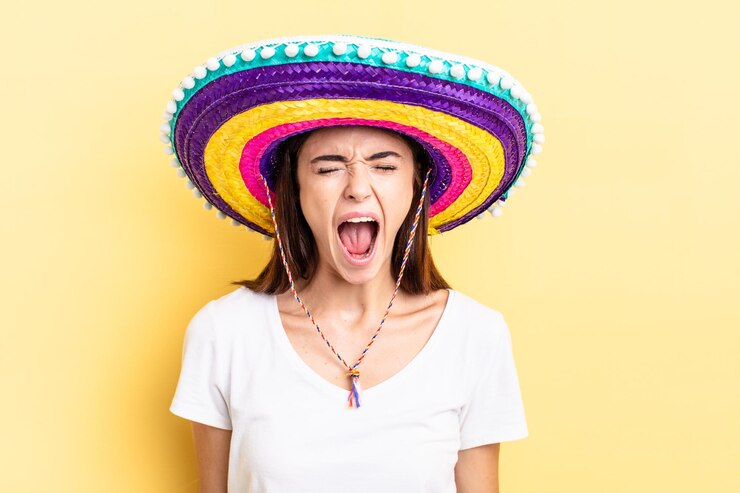 Foto jovem mulher hispânica gritando agressivamente, parecendo muito zangada. conceito de chapéu mexicano