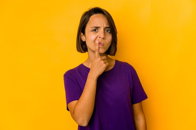 Jovem mulher hispânica isolada em amarelo pensando e olhando para cima, sendo reflexiva, contemplando, tendo uma fantasia.