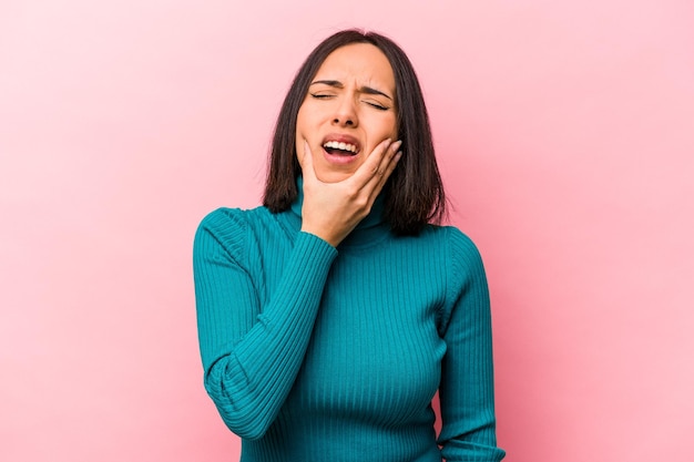 Jovem mulher hispânica isolada em fundo rosa com uma forte dor molar de dentes