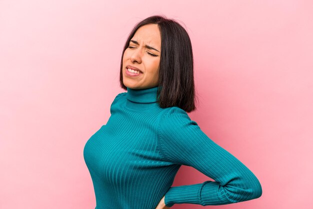 Foto jovem mulher hispânica isolada em fundo rosa, sofrendo uma dor nas costas