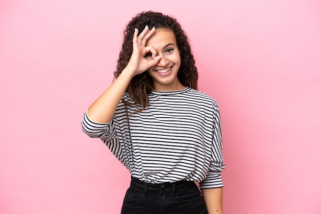 Jovem mulher hispânica isolada no fundo rosa mostrando sinal de ok com os dedos