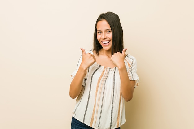 Jovem mulher hispânica, levantando os dois polegares, sorrindo e confiante.