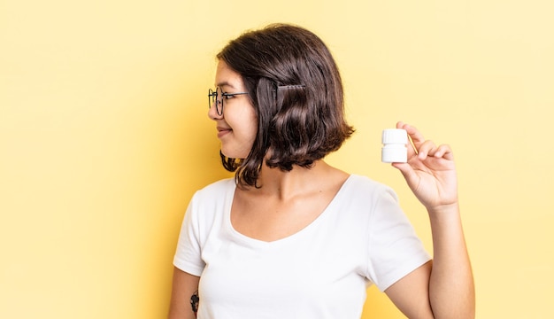 Jovem mulher hispânica na vista de perfil, pensando, imaginando ou sonhando acordada. conceito de pílulas para doenças