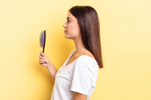 Jovem mulher hispânica na vista de perfil pensando, imaginando ou sonhando acordado. conceito de escova de cabelo