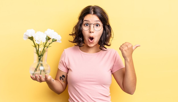 Jovem mulher hispânica olhando atônita na descrença. conceito de vaso de flores