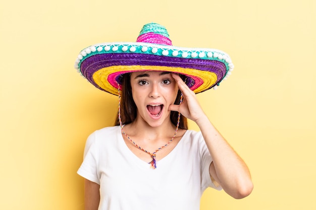 Jovem mulher hispânica olhando feliz, atônita e surpresa. conceito de chapéu mexicano