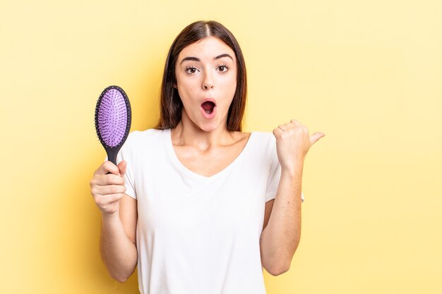 Jovem mulher hispânica parecendo espantada com a descrença. conceito de escova de cabelo