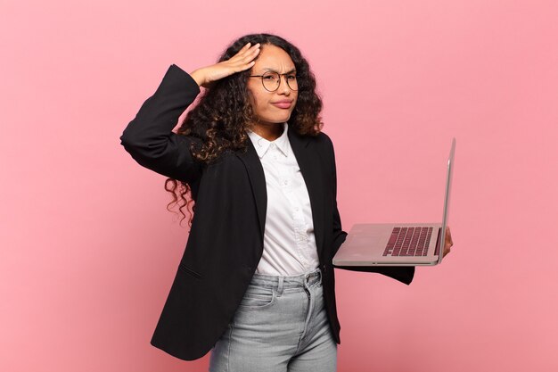 Jovem mulher hispânica parecendo feliz, atônita e surpresa, sorrindo e percebendo uma boa notícia incrível. conceito de laptop