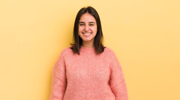 Jovem mulher hispânica parecendo feliz e pateta com um largo sorriso maluco e olhos bem abertos