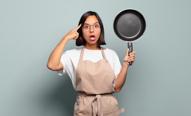 Jovem mulher hispânica parecendo surpresa, boquiaberta, chocada, percebendo um novo pensamento, ideia ou conceito