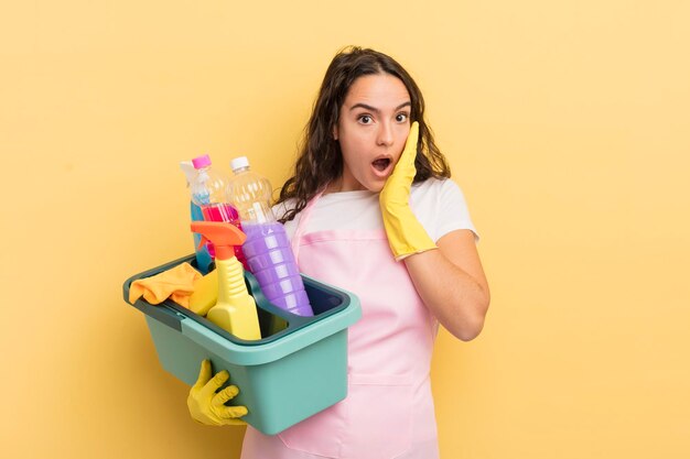 Jovem mulher hispânica se sentindo chocada e assustada com o trabalho doméstico um conceito de produtos limpos