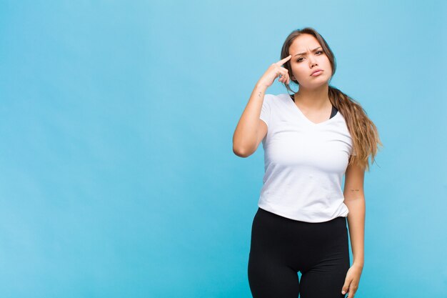 Jovem mulher hispânica se sentindo confusa e perplexa, mostrando que você é louco, louco ou maluco