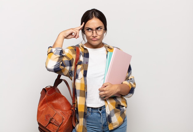 Jovem mulher hispânica se sentindo confusa e perplexa, mostrando que você é louco, louco ou maluco