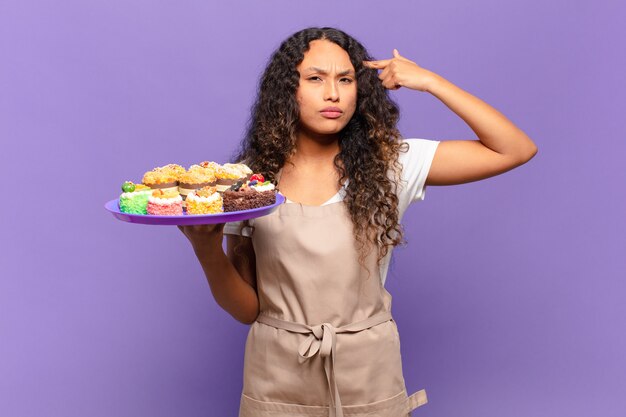 Foto jovem mulher hispânica se sentindo confusa e perplexa, mostrando que você é louco, louco ou maluco